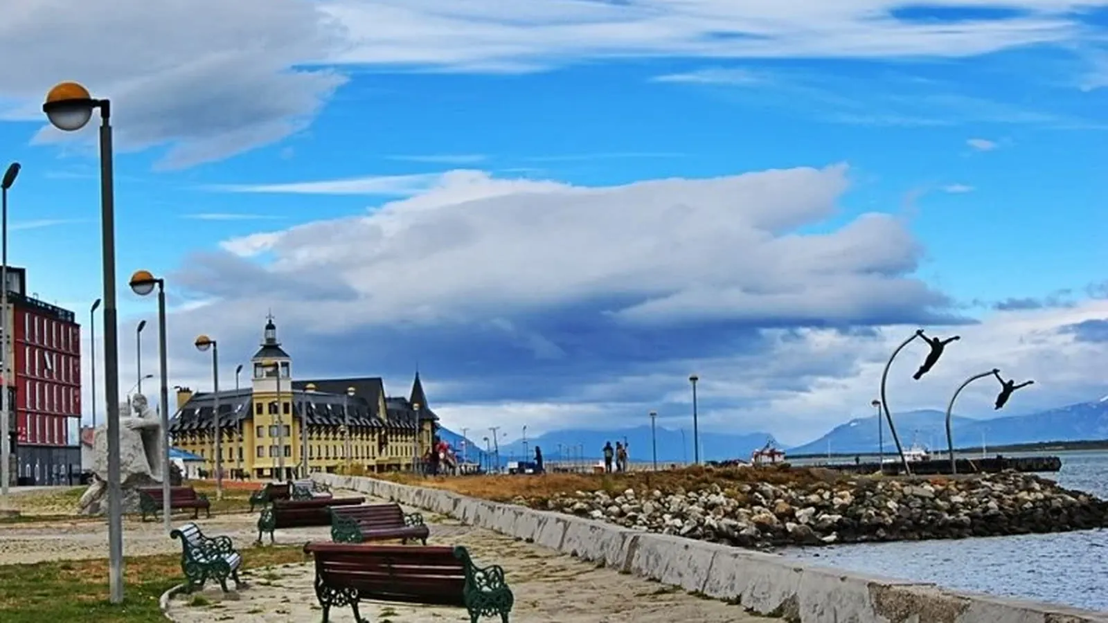 A Puerto Natales street with austral architecture and the coastal landscape beyond.